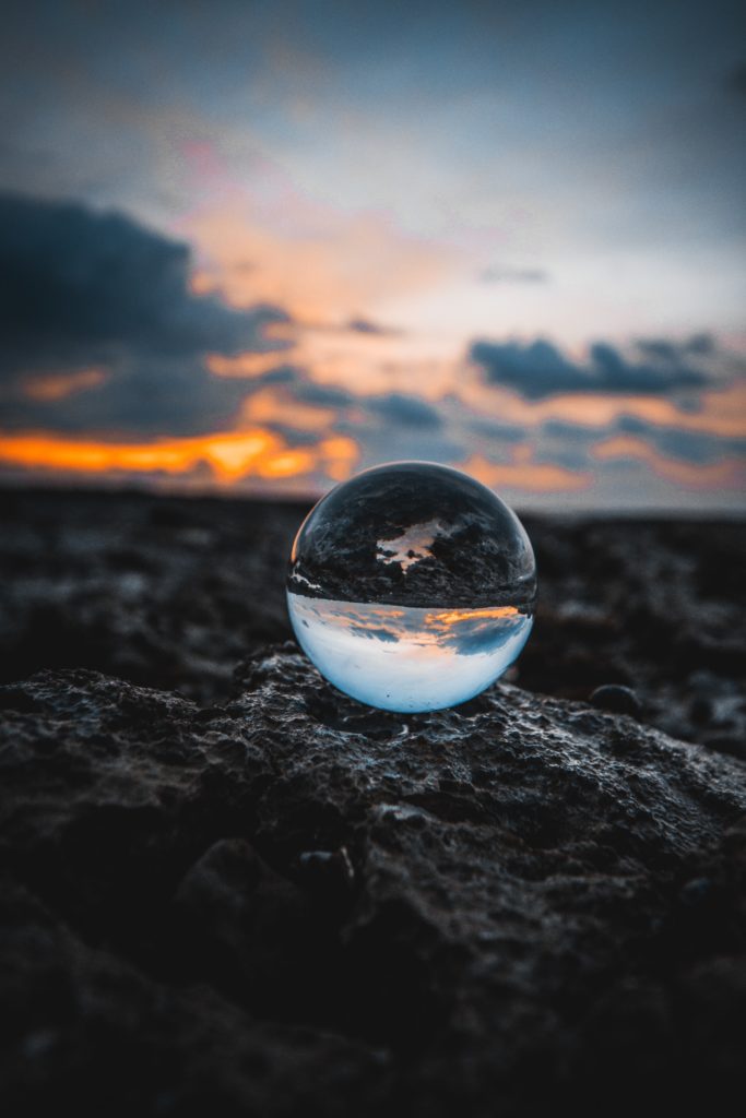 A glass ball sitting on the sand.