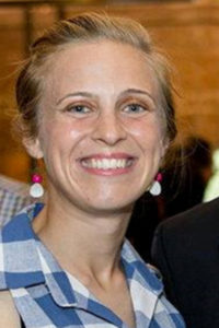 A woman with her hair pulled back smiles at a camera.