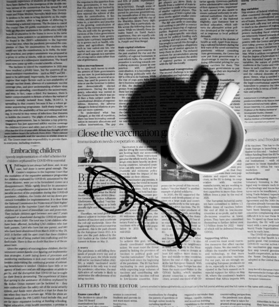 A newspaper with coffee and glasses sitting on top.