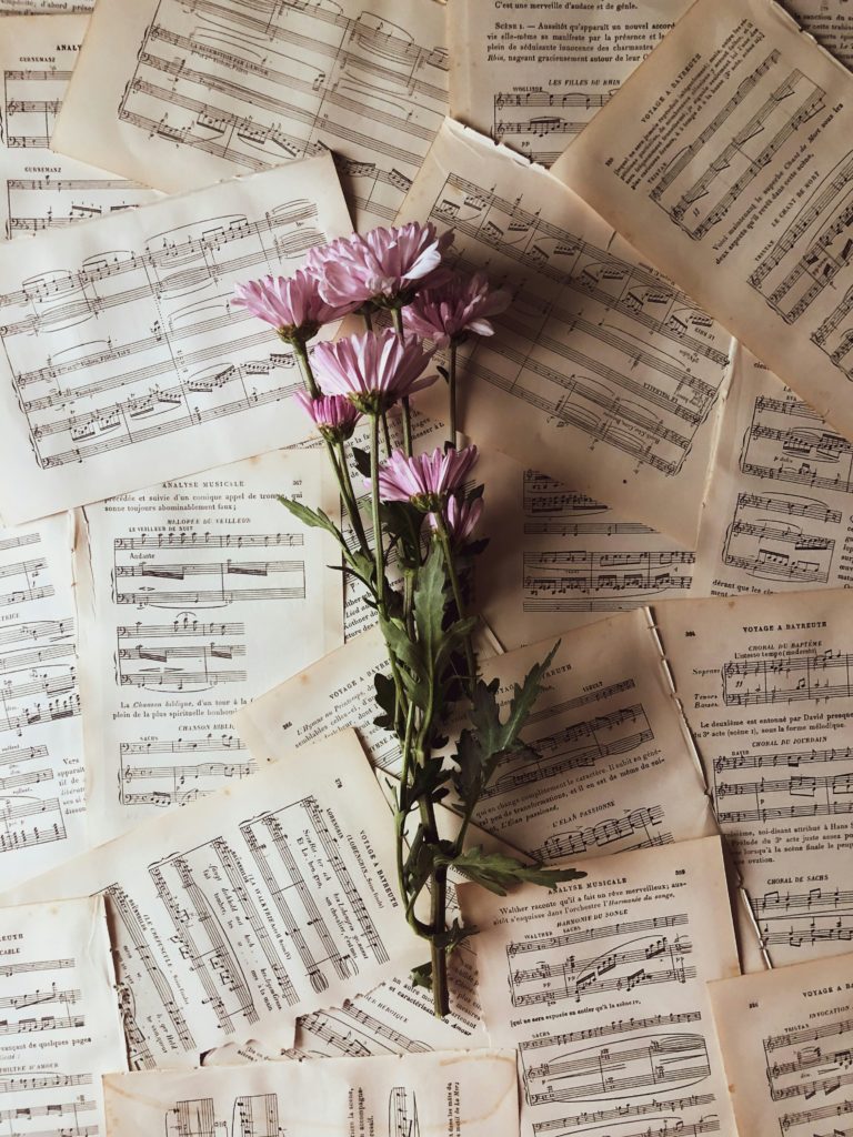 A set of purple flowers with sheet music on top.